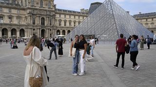 سياح يلتقطون صورًا أمام الهرم في متحف اللوفر، في باريس، فرنسا، الاثنين، 20 يونيو/حزيران 2022
