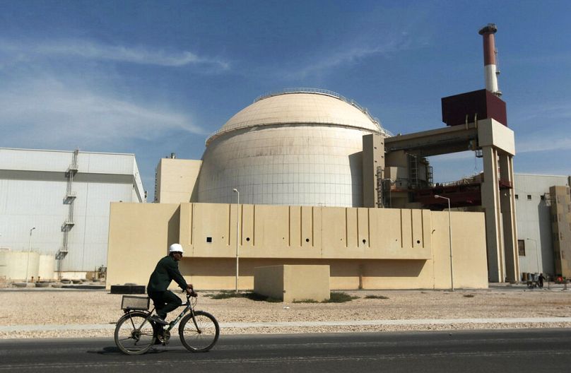 A worker rides a bicycle in front of the reactor building of the Bushehr nuclear power plant, just outside the southern city of Bushehr, Iran, Oct. 26, 2010.