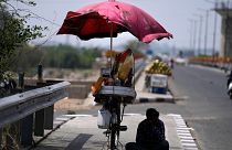 A snacks vendor sits under a shade and waits for customer on a hot summer afternoon in Jammu, India, May 19, 2022. 