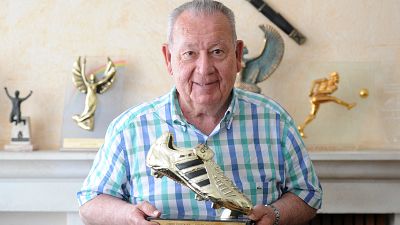 Former French international football player Just Fontaine poses with a trophy for the 1958 football World Cup top-scoring record.