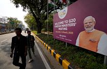 Commuters walk past a banner with Indian Prime Minister's Narendra Modi photograph welcoming delegates of G20 foreign ministers meeting, in New Delhi, India, March 1, 2023. 