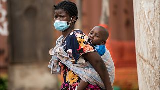 أم تحمل طفلها على ظهرها في ملاوي، أحد أكثر البلدان فقرا وأقلها تطورا في العالم