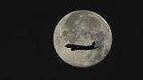 An aeroplane silhouette across the moon