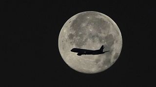 An aeroplane silhouette across the moon