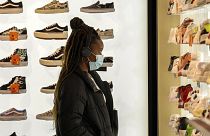 A woman wears a protective mask as she looks at shoes in Rue Neuve in Brussels, Belgium, Nov. 27, 2021.