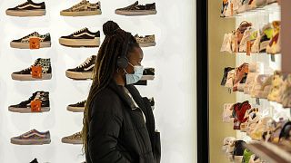 A woman wears a protective mask as she looks at shoes in Rue Neuve in Brussels, Belgium, Nov. 27, 2021.