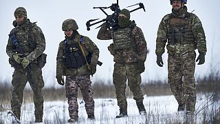 Ukrainian soldiers carrying a drone in combat