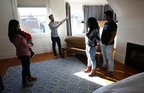 Ryan Booth, (left center) with his guests, as he welcomes them to his home and the bedroom he renting to them through Airbnb, in San Francisco, Calif., on Feb. 5, 2018. 