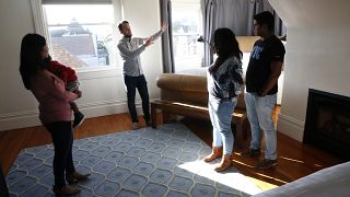 Ryan Booth, (left center) with his guests, as he welcomes them to his home and the bedroom he renting to them through Airbnb, in San Francisco, Calif., on Feb. 5, 2018.