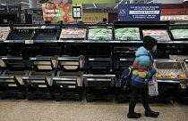 فتاة داخل متجر"أسدا" شرق العاصمة البريطانية لندن، تسير بجوار رفوف فواكه وخضروات خالية أو تكاد،  25 فبراير 2023.