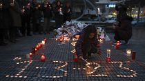 Una niña enciende una vela, en memoria de las víctimas de la colisión de trenes, frente a la estación de tren de Larissa, al norte de Atenas, Grecia, el 2 de marzo de 2023.