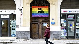 Un homme passe devant un drapeau sur lequel on peut lire : "Pas de mafia" à Palerme, en Italie, le mardi 17 janvier 2023.
