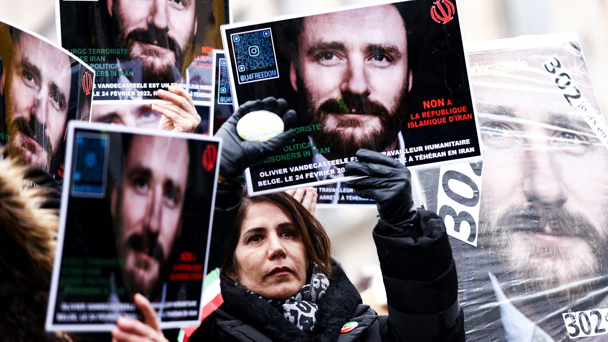Demonstrators hold placards with the portrait of detained Belgian aid worker Olivier Vandecasteele, as they take part in a solidarity rally in Brussels on January 22, 2023. 