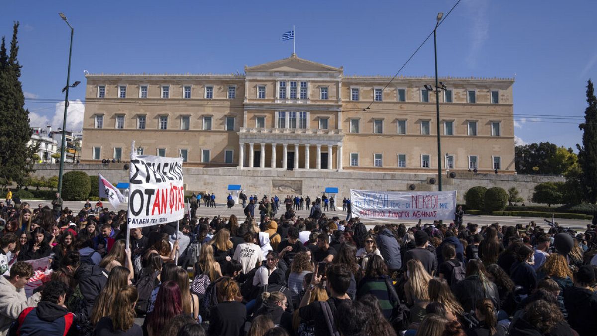 University students seat on the road in front of the greek Parliament as they pay respects to the victims of the train accident, in Athens, Friday, March 3, 2023