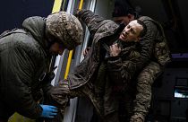 Ukrainian military medics help their wounded comrade to get out from an ambulance after arriving from the battlefield to the field hospital near Bakhmut