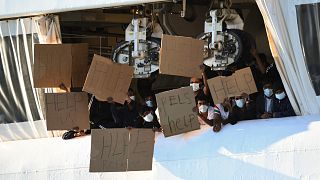 Migrants hold banners asking for help, from a deck of the Norway-flagged Geo Barents ship operated by Doctors Without Borders, in Catania's port, Sicily in 2022.
