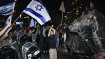 Israeli mounted police officers disperse demonstrators as they block a main road during a protest.