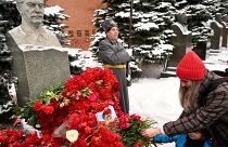 Eine Frau legt Blumen an der Stalin-Büste nieder
