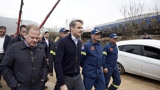 Görögország miniszterelnöke, Kiriakos Micotakisz (a második balra) és Kosztasz Karamanlisz közlekedési miniszter felkereste a vonatütközés helyszínét