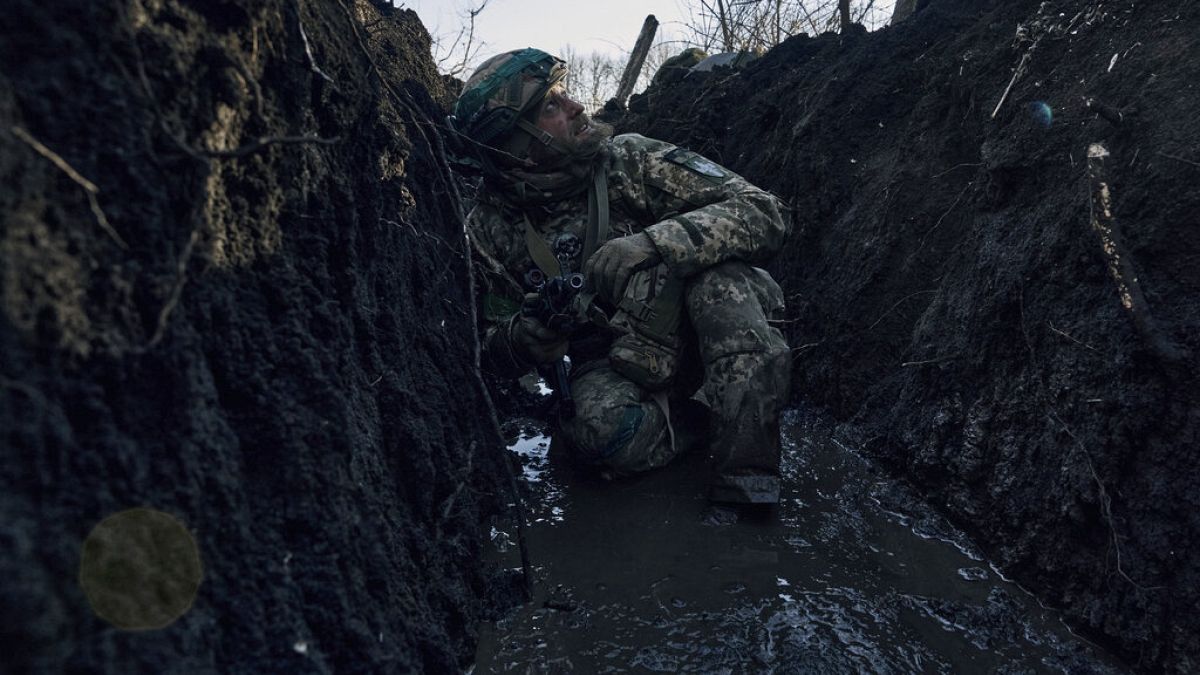 A Ukrainian soldier takes cover in a trench under Russian shelling on the frontline close to Bakhmut, Donetsk region, Ukraine, Sunday, March 5, 2023.
