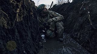 A Ukrainian soldier takes cover in a trench under Russian shelling on the frontline close to Bakhmut, Donetsk region, Ukraine, Sunday, March 5, 2023.