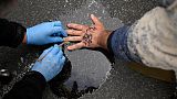 A policeman works on the hand of a man who has glued himself on the street in Berlin.   -  