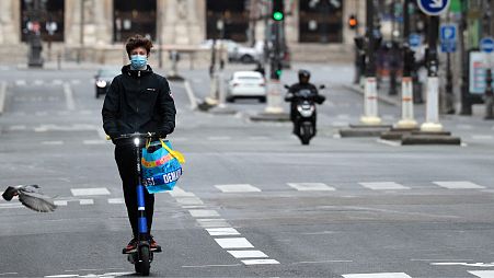 A man rides on an electric scooter along a street in Paris.