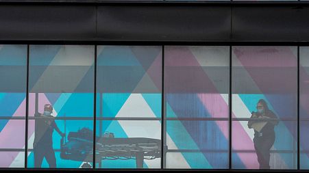 FILE - Health care workers look out the window at NY Presbyterian and Mount Sinai from an overpass at Mount Sinai Hospital, Tuesday, March 16, 2021