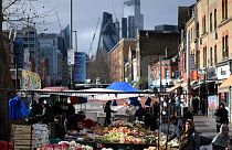 Customers shop for fruit and vegetables at a market stall in east London on February 20, 2023.