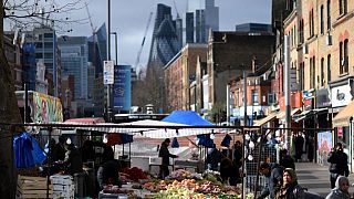 Customers shop for fruit and vegetables at a market stall in east London on February 20, 2023.