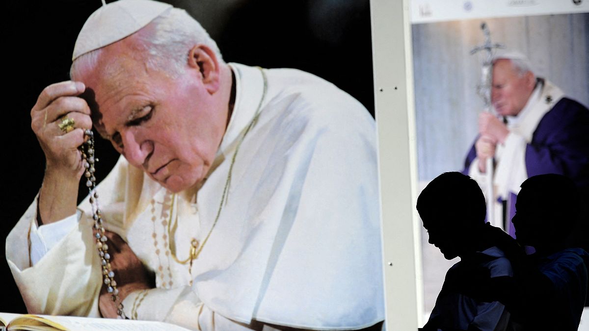الصورة التي التقطت في 29 أبريل 2011 في روما تظهر أطفالا يمشون أمام صور عملاقة للبابا الراحل يوحنا بولس الثاني.