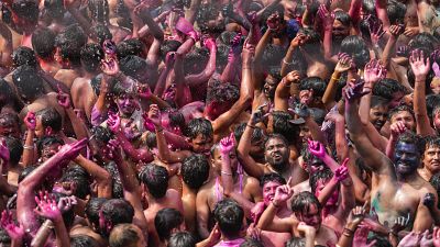 Indian revelers, faces smeared with colored powder, dance during celebrations to mark Holi, the Hindu festival of colors in Prayagraj, India, on Thursday March, 9, 2023.