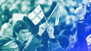 A young woman holds a Georgian national flag and an EU flag during a protest near the Georgian parliament building in Tbilisi, 9 March 2023