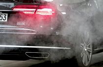 A luxury Audi car is surrounded by exhaust gases as it is parked with a running engine in front of the Chancellery in Berlin, Germany.