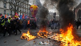 Protesters walk past a burning pallets during a demonstration in Paris, Saturday, March 11, 2023. 