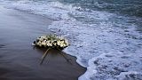 Una corona de flores flota en el mar Mediterráneo, lanzada por las personas que terminaron una marcha de protesta en la playa en el lugar del naufragio, el 11 de marzo de 2023