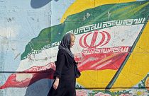 سيدة إيرانية تسير أمام جدارية لعلم إيران في أحد شوارع العاصمة طهران 19/09/2019