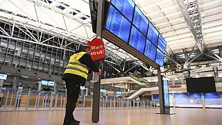 A szakszervezet munkatársa a sztrájkra figyelmeztető táblát helyez ki a hamburgi repülőtéren