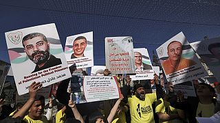 أشخاص يحملون لافتات عليها صور فلسطينيين محتجزين في السجون الإسرائيلية خلال "ماراثون حرية الحركة في فلسطين" في بيت لحم بالضفة الغربية المحتلة، 10 مارس 2023.
