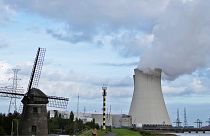 Steam billows from a nuclear power plant next to an old windmill in Doel, Belgium.