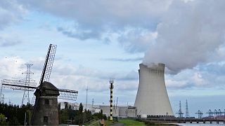 Una central nuclear emite vapor junto a un viejo molino de viento en Doel (Bélgica).