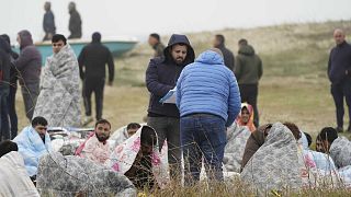 Gerettete Migranten sitzen in Decken gehüllt an einem Strand in der Nähe von Cutro, Süditalien, 26. Februar 2023.