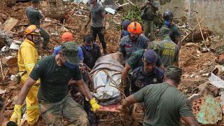 Rescue workers and volunteers carry the body of a landslide victim near Barra do Sahy beach after heavy rains in the coastal city of Sao Sebastiao, Brazil