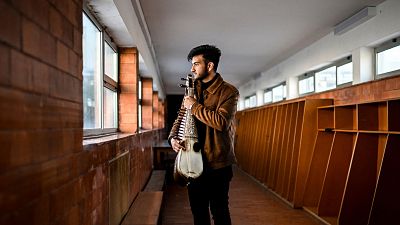 19 years old music student Ramiz from Afghanistan poses holding an Afghan instrument called rubab at the Music Conservatory of Braga, Portugal.