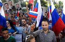 Sírios exibem fotografias de Bashar al Assad e bandeiras russas, durante uma marcha de agradecimento à Rússia pelasua intervenção na Síria, em 2015.