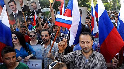  Syrians holding photos of Syrian President Bashar Assad and Russian flags, during a protest to thank Moscow for its intervention in Syria, 2015.