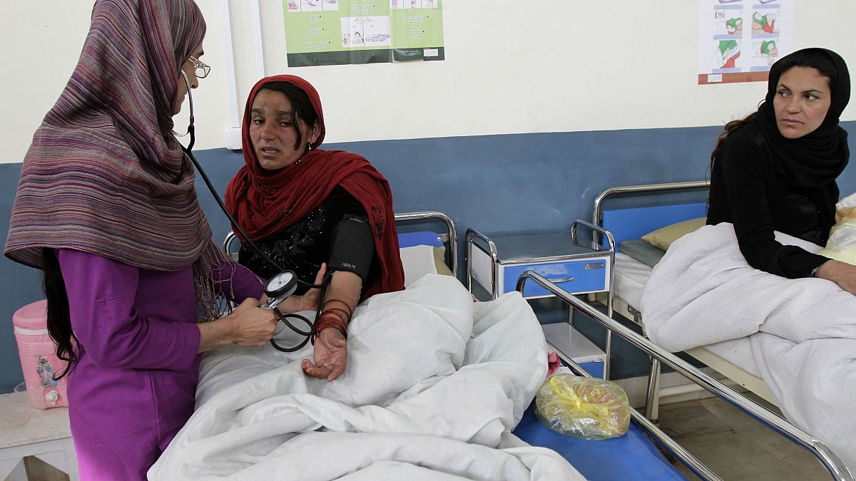 الصورة لمرضة تعاين امرأة في مستشفى أحمد شاه بابا شرق كابول، أفغانستان