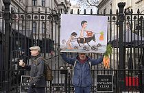 Artist Kaya Mar poses outside Downing Street with his satirical painting of British Prime Minister Rishi Sunak and his Chancellor of the Exchequer Jeremy Hunt