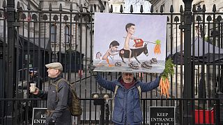 Artist Kaya Mar poses outside Downing Street with his satirical painting of British Prime Minister Rishi Sunak and his Chancellor of the Exchequer Jeremy Hunt