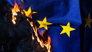 An EU flag burns.